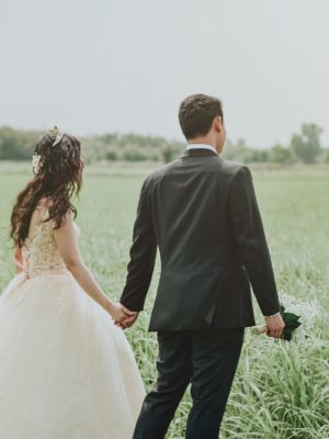 Husband and wife walking in a grass field.