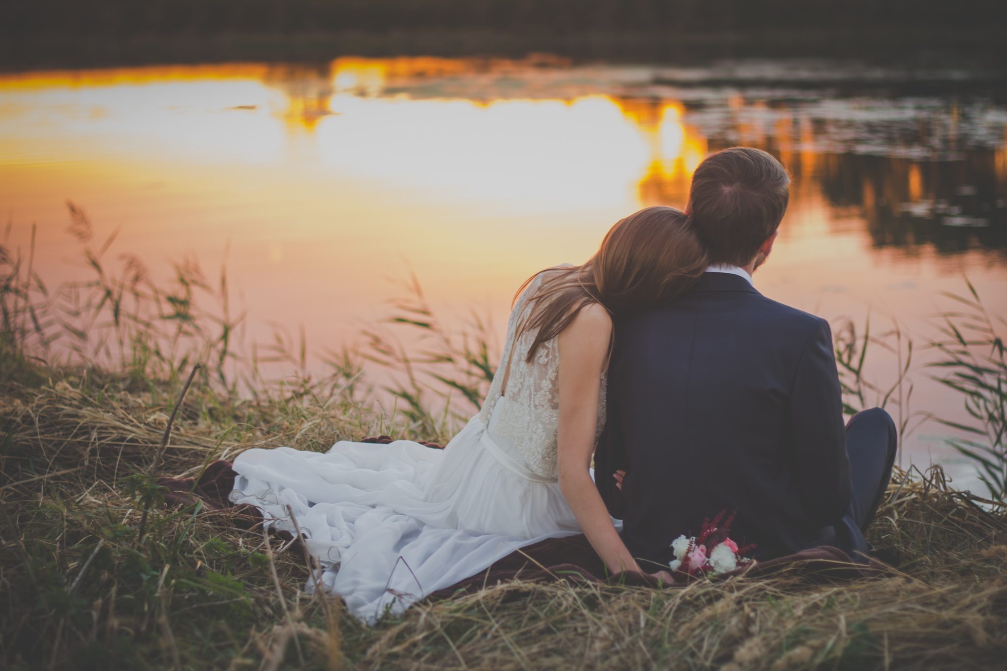 Young married couple watching a sunset over a lake