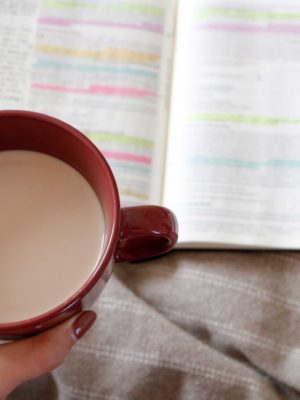 Woman's hand holding coffee while studying her bible