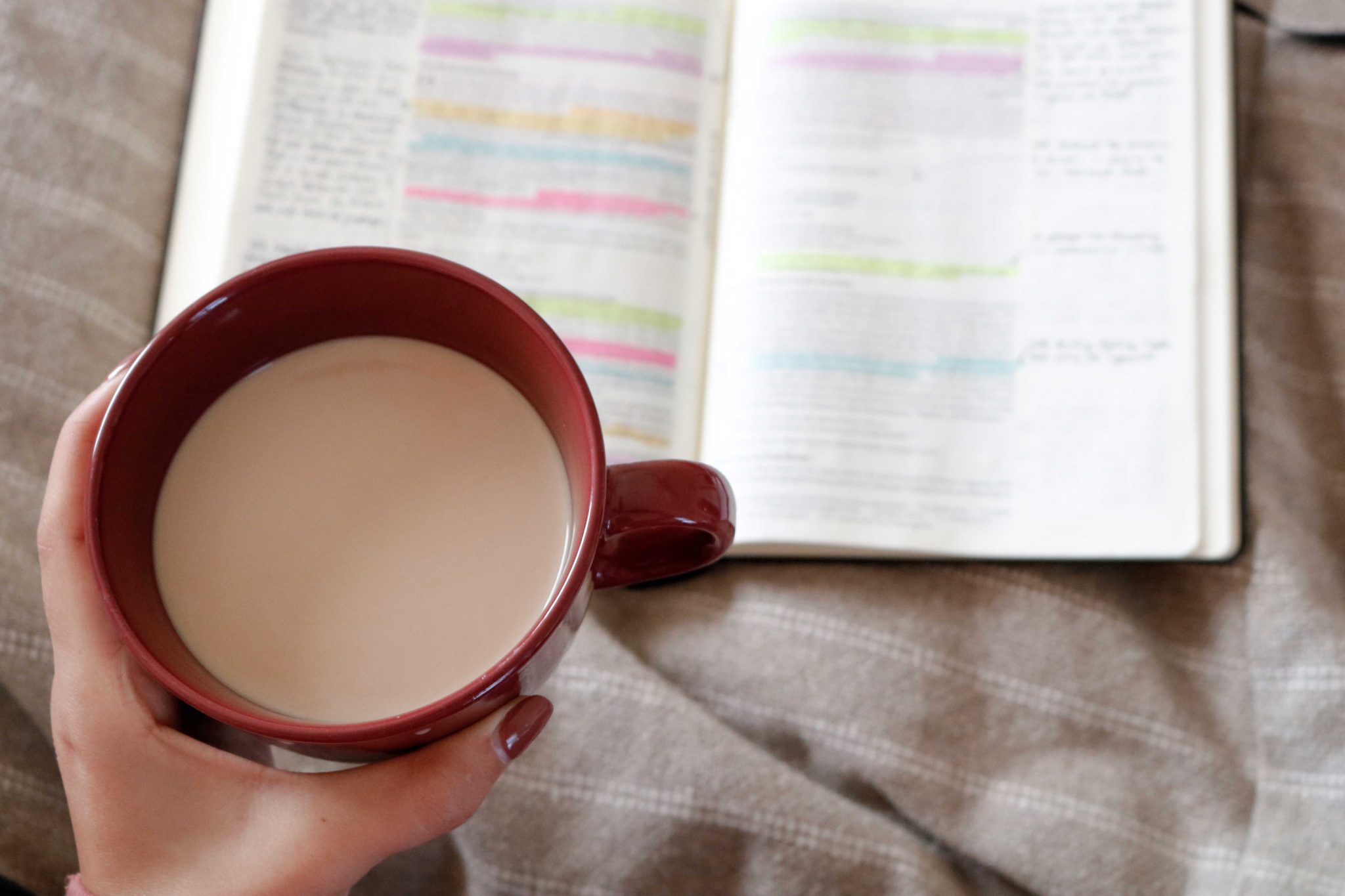 Woman's hand holding coffee while studying her bible