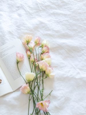 Christian book on white blanket with flowers and glasses